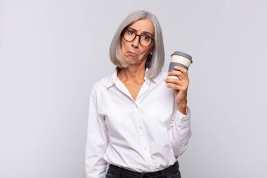 Orta yaşlı bir kadın üzgün ve mızmızlanıyor. Mutsuz bir bakışla ağlıyor. Olumsuz ve hüsrana uğramış bir kahve konseptiyle ağlıyor.