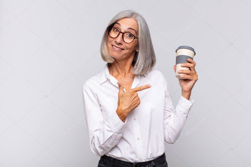 middle age woman looking excited and surprised pointing to the side and upwards to copy space coffee concept