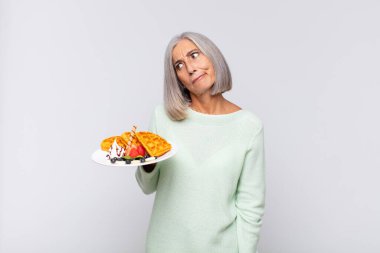 Orta yaşlı bir kadın üzgün, üzgün ya da kızgın ve olumsuz bir tavır takınıyor, anlaşmazlık içinde kaşlarını çatıyor. kahvaltı kavramı