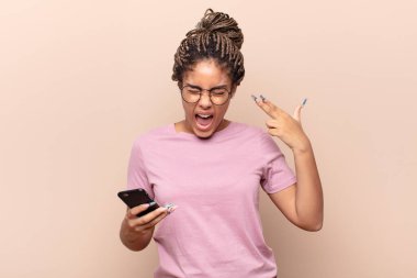 Genç afro kadın mutsuz ve stresli görünüyor, intihar jesti silahla işaret ediyor, kafasını işaret ediyor. akıllı telefon kavramı
