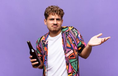 Genç adam şaşkın ve şaşkın, şüpheci, farklı seçenekleri tartıyor ya da komik bir ifadeyle seçiyor. tatil kavramı