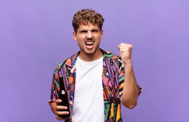 Genç adam öfkeli bir ifadeyle ya da yumruklarıyla başarıyı kutlarken agresif bir şekilde bağırıyor. tatil kavramı