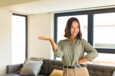 Genç Latin kadın gülümsüyor, kendinden emin, başarılı ve mutlu hissediyor, fotokopi alanında konsept ya da fikir gösteriyor. ev kavramı