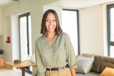 Büyük, dost canlısı, kaygısız gülüşü olan genç Latin bir kadın. Olumlu, rahat, mutlu ve ürpertici görünüyor. ev kavramı