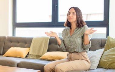 Genç Latin kadın şaşkın ve şaşkın hissediyor, doğru cevap ya da karardan emin değil, bir seçim yapmaya çalışıyor. ev kavramı