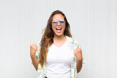 Genç ve güzel bir kadın öfkeli bir ifadeyle ya da yumruklarıyla başarıyı kutlarken agresif bir şekilde bağırıyor. turizm konsepti