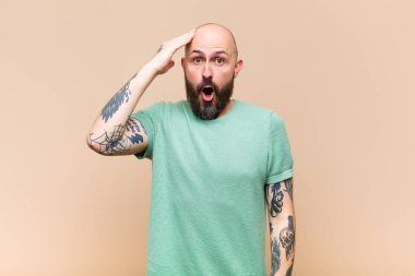 Genç kel ve sakallı adam mutlu, şaşkın ve şaşırmış görünüyor, gülümsüyor ve inanılmaz ve inanılmaz iyi haberleri fark ediyor.