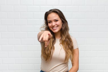 Tatmin olmuş, kendine güvenen, dost canlısı bir gülümsemeyle kameraya bakıp seni seçiyor.