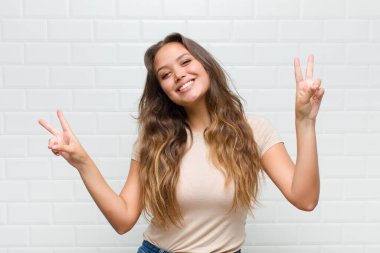 Gülümseyen ve mutlu görünen, dost canlısı ve tatmin olmuş, zafer ya da barış işareti yapan iki elinle