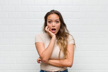 Şok ve inançsızlıkla ağzı açık, elleri yanakları ve kolları çaprazlanmış, sersemlemiş ve şaşkın.