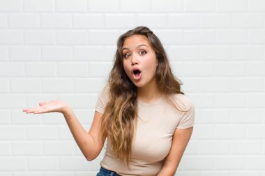 Şaşırmış ve şoke olmuş bir halde, çenesi düşmüş bir objeyi elinde açık bir elle tutarken.