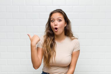 İnançsızlıktan şaşkın şaşkın bakıyor, yan taraftaki objeyi işaret ediyor ve 