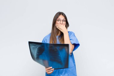 Genç ve güzel hemşire elleri ile ağzını kapatıyor, şok olmuş, şaşırmış bir ifadeyle, sır saklıyor ya da 