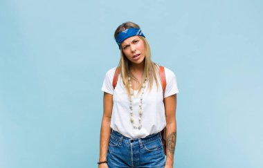 young pretty hippie woman feeling puzzled and confused, with a dumb, stunned expression looking at something unexpected