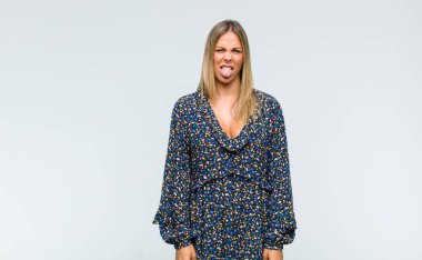 Genç ve güzel bir kadın, tiksinmiş ve rahatsız olmuş hissediyor. Dilini dışarı çıkarıyor, iğrenç ve iğrenç bir şeyden hoşlanmıyor.