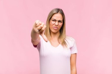 Genç, güzel bir kadın kızgın, sinirli, hayal kırıklığına uğramış ya da hoşnutsuz, ciddi bir bakışla başparmağını kaldırıyor.