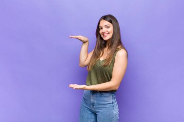 Sen güzel bir kadınsın. İki eli de kenarda duran bir objeyi tutuyorsun. Bir objeyi gösteriyor, sunuyor ya da reklamını yapıyorsun.