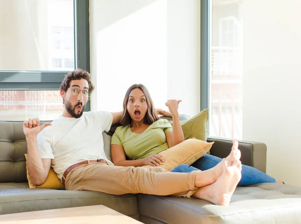 Young Couple Looking Astonished Disbelief Pointing Object Side Saying Wow — Stock Photo, Image