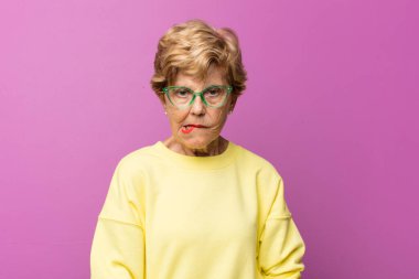 Yaşlı güzel kadın şaşkın ve şaşkın görünüyor. Sinirli bir hareketle dudağını ısırıyor. Sorunun cevabını bilmiyor.