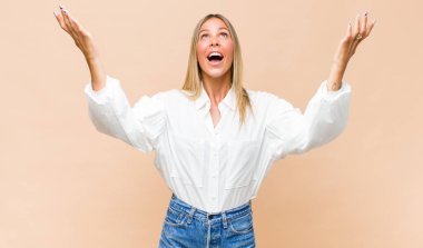 Genç, güzel bir kadın kendini mutlu, şaşkın, şanslı ve şaşırmış hissediyor. Zaferi kutlarken iki elini de havaya kaldırıyor.