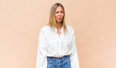 Genç ve güzel bir kadın üzgün ve mızmızlanıyor, mutsuz bir bakışla, negatif ve hayal kırıklığına uğramış bir tavırla ağlıyor.