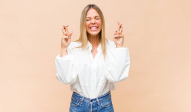 Genç, güzel bir kadın gülümsüyor ve endişeyle iki parmağını çaprazlıyor, endişeli ve iyi şanslar diliyor.