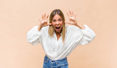 Genç, güzel bir kadın panik ya da öfke içinde bağırıyor. Şok olmuş, korkmuş ya da öfkeli. Elleri başının yanında.