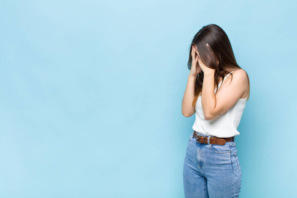 youn pretty woman covering eyes with hands with a sad, frustrated look of despair, crying, side view