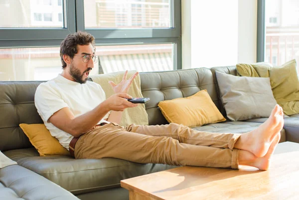 young bearded cool man sitting on a couch at home