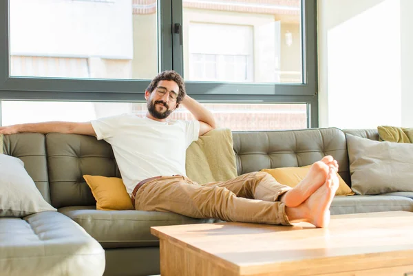 young bearded cool man sitting on a couch at home