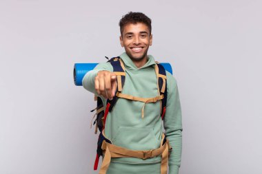 young hiker man pointing at camera with a satisfied, confident, friendly smile, choosing you