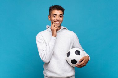 young man smiling happily and daydreaming or doubting, looking to the side. soccer concept