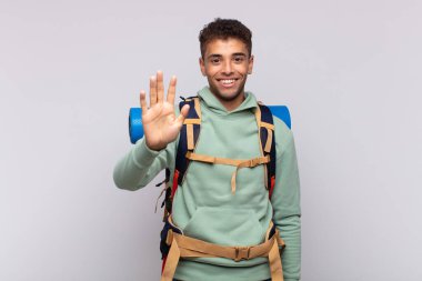 young hiker man smiling and looking friendly, showing number five or fifth with hand forward, counting down