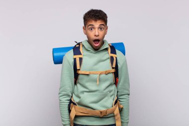 young hiker man looking very shocked or surprised, staring with open mouth saying wow