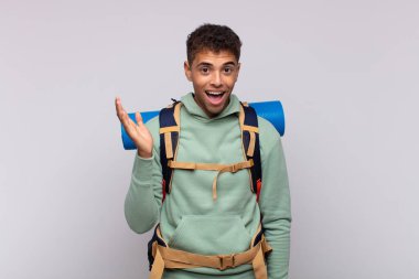 young hiker man feeling happy, surprised and cheerful, smiling with positive attitude, realizing a solution or idea