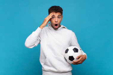 young man looking happy, astonished and surprised, smiling and realizing amazing and incredible good news. soccer concept