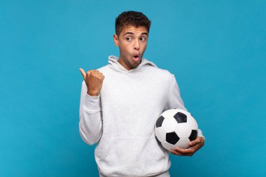 young man looking astonished in disbelief, pointing at object on the side and saying wow, unbelievable. soccer concept