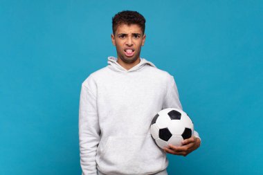 young man feeling disgusted and irritated, sticking tongue out, disliking something nasty and yucky. soccer concept