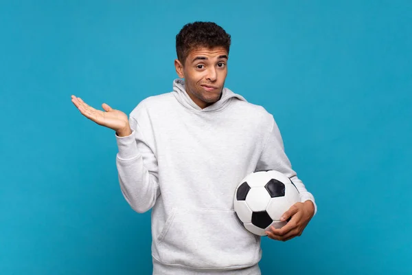 年轻人感到困惑和困惑 权衡或以滑稽的表情选择不同的选项 足球概念 — 图库照片