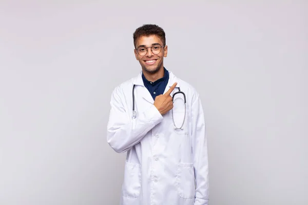 Joven Médico Sonriendo Alegremente Sintiéndose Feliz Señalando Hacia Lado Hacia —  Fotos de Stock