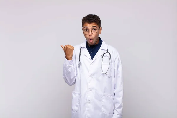 Young Physician Man Looking Astonished Disbelief Pointing Object Side Saying — Φωτογραφία Αρχείου