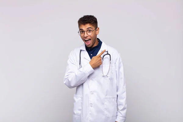 Молодий Лікар Чоловік Виглядає Схвильованим Здивованим Вказуючи Бік Вгору Щоб — стокове фото