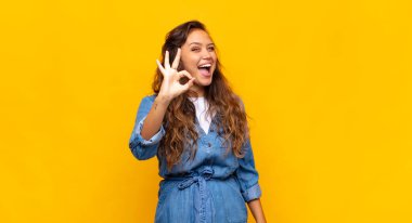 Kız kendini başarılı ve tatmin olmuş hissediyor, ağzı açık gülümsüyor, elle işaret veriyor.