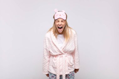 Genç, güzel bir kadın pijama giyiyor, agresif bir şekilde bağırıyor, kızgın, sinirli, öfkeli ya da sinirli görünüyor, hayır diye bağırıyor.