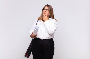 Genç mimar kadın düşünüyor, kuşkulu ve şaşkın hissediyor, farklı seçeneklerle, hangi kararı vereceğini merak ediyor.