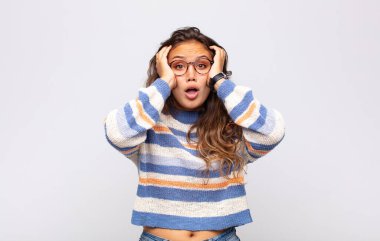 Kız mutsuz, korkmuş ya da endişeli görünüyor, ağzı sonuna kadar açık ve iki kulağını da elleriyle kapatıyor.