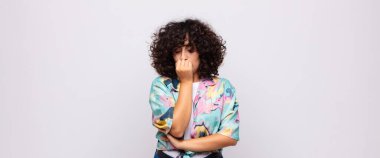 Kadın ciddi, düşünceli ve endişeli, elleri çenesine bastırılmış, yan bakıyor.