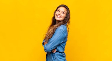 Kız neşeyle gülümsüyor, mutlu, tatmin olmuş ve rahatlamış hissediyor, kollarını kavuşturup yan tarafa bakıyor.