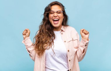 Kız son derece mutlu ve şaşırmış görünüyor, başarıyı kutluyor, bağırıyor ve zıplıyor