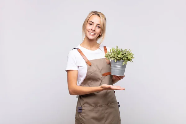 Νεαρή Κηπουρός Γυναίκα Χαμογελά Χαρούμενα Αισθάνεται Χαρούμενος Και Δείχνει Μια — Φωτογραφία Αρχείου